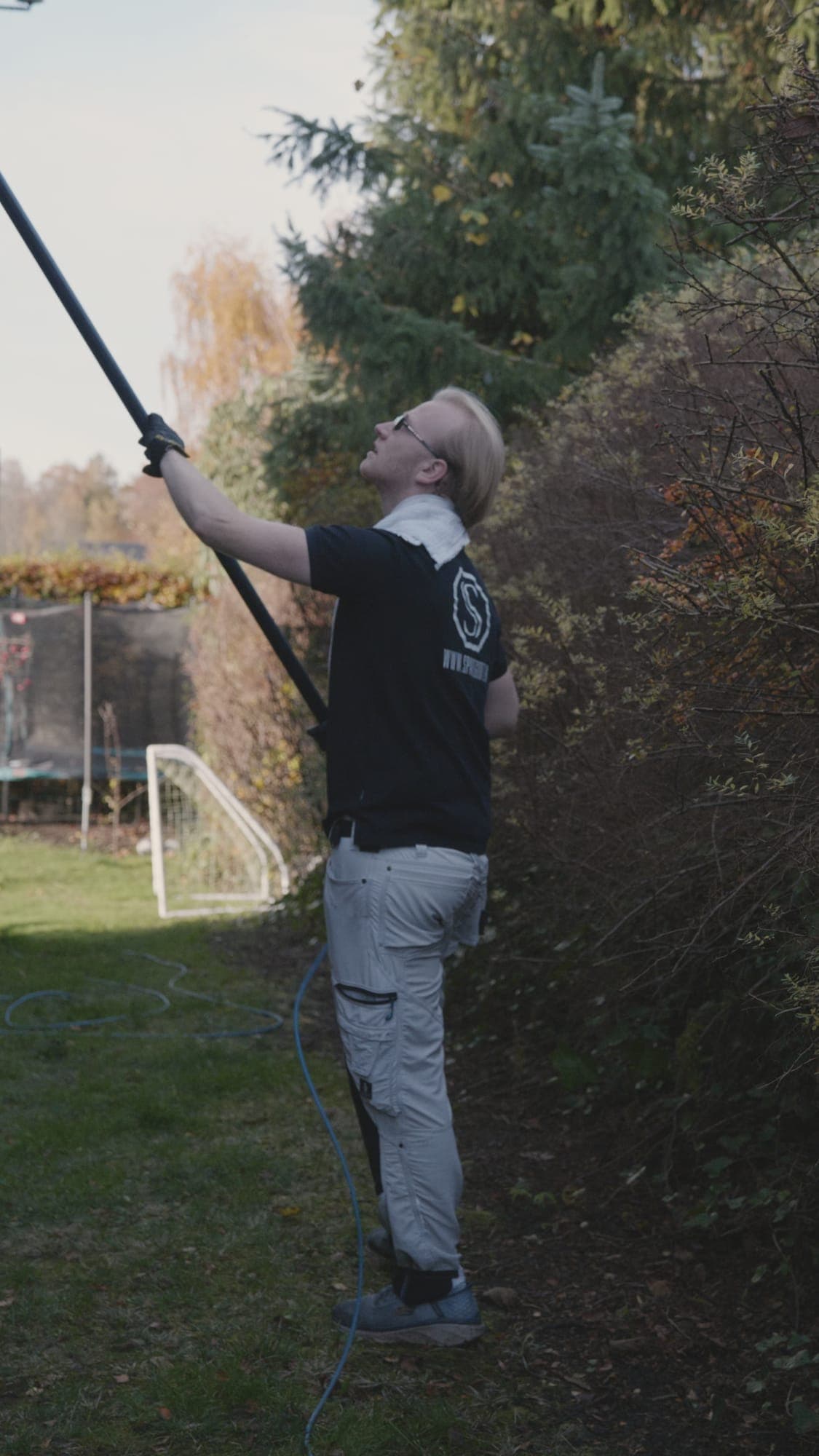 Sparegodt medarbejder pudser vinduer med teleskopstang